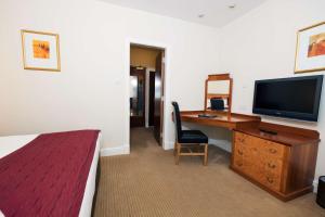 a room with a bed, desk, chair and television at Pitbauchlie House Hotel - Sure Hotel Collection by Best Western in Dunfermline