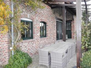 eine Terrasse mit einem Holztisch und Stühlen auf einem Backsteingebäude in der Unterkunft Vakantiehuis Montezicht in de groene heuvels van Dranouter in Heuvelland