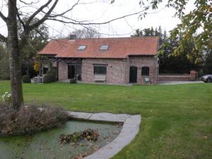 een stenen huis met een rood dak in een tuin bij Vakantiehuis Montezicht in de groene heuvels van Dranouter in Heuvelland