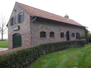 a brick building with a green door and a wall at Vakantiehuis Montezicht in de groene heuvels van Dranouter in Heuvelland