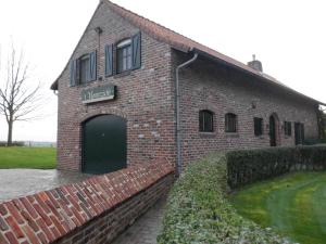 a red brick building with a green garage at Vakantiehuis Montezicht in de groene heuvels van Dranouter in Heuvelland