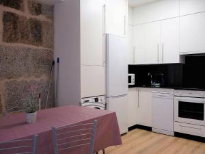 una cocina con armarios blancos y una mesa. en Delightful Apartment in Ourense overlooking the City, en Ourense