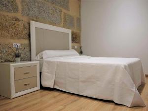 a bedroom with a white bed and a night stand at Apartment in Ourense near Thermal Baths in Ourense