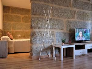 a living room with a tv and a stone wall at Apartment in Ourense near Thermal Baths in Ourense