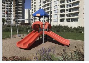 a playground with a red slide and an umbrella at Marina Casino Playa in Coquimbo
