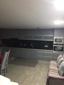 a kitchen with gray cabinets and a couch in a room at CasaMesquita in Cabeceiras de Basto