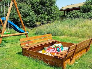 6 person holiday home in R m في Bolilmark: مقعد خشبي مع صندوق رملي في العشب