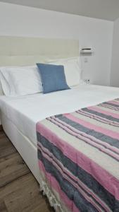 uma grande cama branca com um cobertor colorido em A.l. KATEKERO em Costa Nova