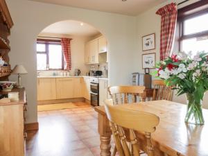 a kitchen with a wooden table and a vase of flowers at Courtyard Cottage in Duns