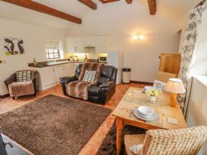 a living room with a table and chairs and a kitchen at Dairy Barn in Pershore