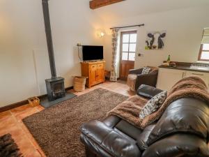 a living room with a leather couch and a fireplace at Dairy Barn in Pershore