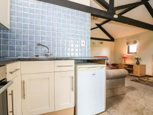 a kitchen with white cabinets and a blue tiled wall at The Granary in Henfield