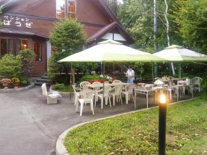 una persona parada frente a un restaurante con mesas y sombrillas en Yamanakako Pension Pause en Yamanakako