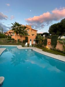 a large swimming pool in front of a house at Marbella Deluxe Rooms in Royal Cabopino Townhouse in Marbella