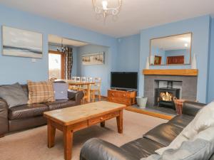 a living room with a couch and a table and a fireplace at Braeside in Coniston