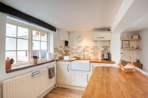 a kitchen with white cabinets and a wooden table at Woodbine Cottage in Market Rasen