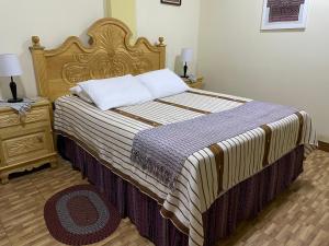 a bedroom with a large bed with a wooden headboard at Hotel-Villas JABEL TINAMIT in Panajachel