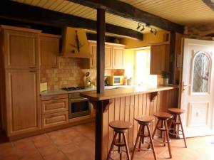 una cocina con armarios de madera y taburetes de bar en Cottage, Plogonnec, en Plogonnec
