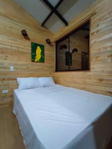 a large white bed in a wooden room with a window at Cabaña Glamping Los Canarios San Rafael, Antioquia in San Rafael