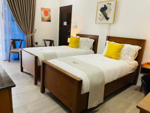 two beds in a hotel room with yellow pillows at Thistle Inn in Panglao