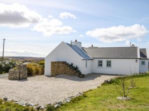 a white cottage with a gravel driveway at Radharc na nOileán in Kincasslagh
