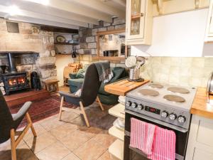 a kitchen with a stove and a living room at Bulmers Cottage in Staithes