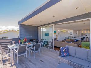 a patio with a couch and a table and chairs at Breezy Views - Simpsons Beach Holiday Home in Whitianga