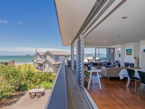 a house with a balcony with a view of the ocean at Breezy Views - Simpsons Beach Holiday Home in Whitianga