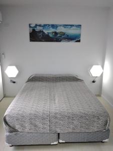 Cama en habitación blanca con 2 luces en kira en Rosario