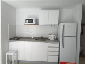 a small kitchen with white cabinets and a refrigerator at kira in Rosario