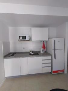 a kitchen with white cabinets and a white refrigerator at kira in Rosario