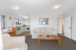 a living room with a couch and a table at Snells Seaside Bach - Snells Beach Holiday Home in Snells Beach