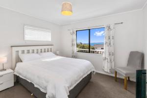 a white bedroom with a large bed and a window at Snells Seaside Bach - Snells Beach Holiday Home in Snells Beach