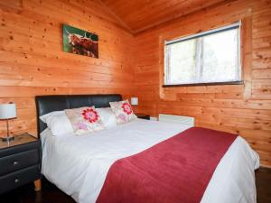a bedroom with a bed in a log cabin at Hazel Lodge in Bodmin
