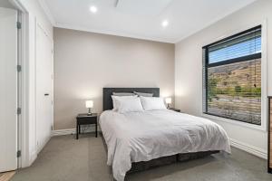 a white bedroom with a large bed and a window at Cardrona Cottage - Cardrona Holiday Home in Cardrona +12 photos