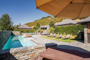 a swimming pool with a table and an umbrella at Cardrona Cottage - Cardrona Holiday Home in Cardrona