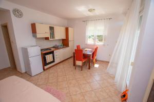 a kitchen with a table and chairs and a kitchen with a refrigerator at Apartments Calida A in Drage