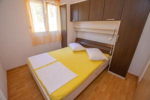 a small bedroom with a yellow and white bed at Apartments Calida A in Drage +18 photos