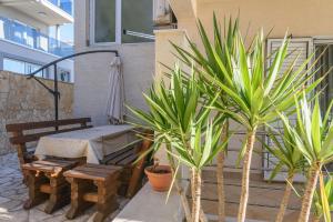 un patio con mesa, banco y plantas en Apartment Helli, en Trogir