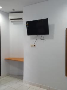 einen Flachbild-TV, der an einer weißen Wand hängt in der Unterkunft C4 homestay in Jakarta