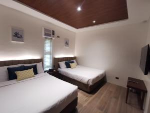 a hotel room with two beds and a television at Tagaytay Country Hotel in Tagaytay