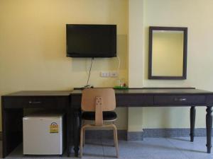 einen Schreibtisch mit einem TV und einem Stuhl in einem Zimmer in der Unterkunft Sri Krungthep Hotel in Bangkok