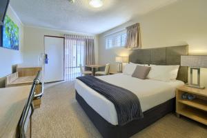 a hotel room with a large bed and a table at Albany Motel & Apartments in Albany