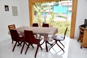 a dining room table with chairs and a window at Kannur Beachway Homestay in Pāppinisseri