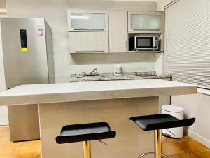 a kitchen with a counter with two stools and a microwave at Holly Bunker in Yabucoa