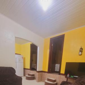 sala de estar con paredes amarillas y TV en Casa da Lia, en Lençóis