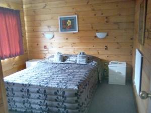 1 dormitorio con 1 cama en una habitación de madera en Cedarwood Lakeside Motel & Conference Venue en Rotorua