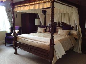 a bedroom with a four poster bed with a canopy at Glebe Country House Tarbet in Arrochar
