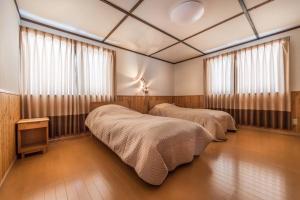 two beds in a room with two windows at Midori House - walking distance to Rusutsu Resort in Rusutsu