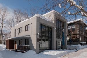 a house with glass windows in the snow at Kitanishi 3 by H2 Life in Kutchan